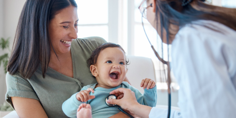 Doctor examining a happy baby with a stethoscope